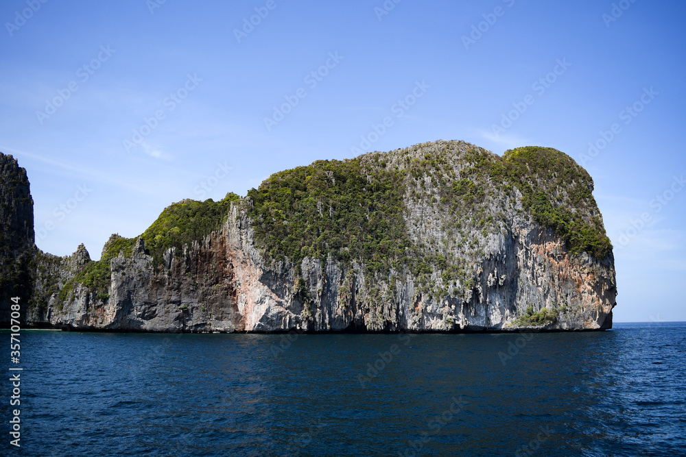 Naklejka premium shot rock in mid of sea with green grass grown on them