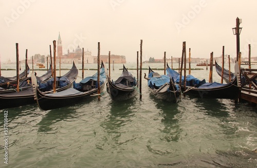 An array of boats parked during rainy day in the Venetian Lagoon enclosed bay of the Adriatic Sea.