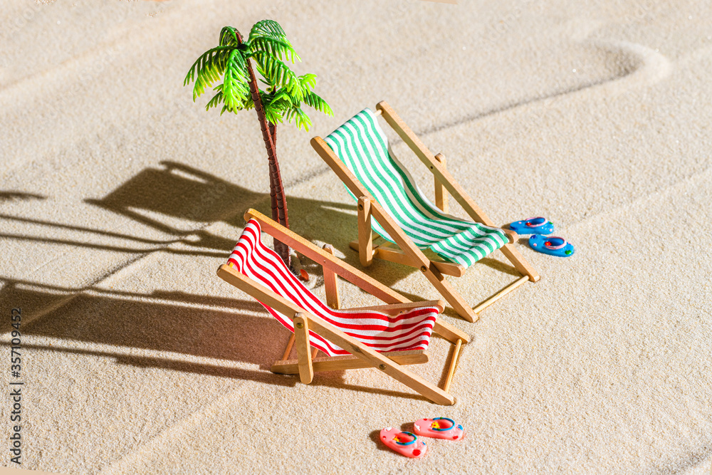Aerial view of two deck chair, sunbed, lounge, flip flops, palm tree on sandy beach. Summer and travel concept. Minimalism Aerial view of two deck chair, sunbed, lounge, flip flops, palm tree on sandy beach. Summer and travel concept. Minimalism