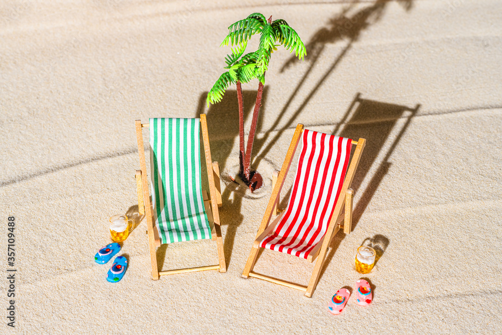Aerial view of two deck chair, sunbed, lounge, big mug of beer, palm tree on sandy beach. Summer and travel concept. Minimalism Aerial view of two deck chair, sunbed, lounge, big mug of beer, palm tree on sandy beach. Summer and travel concept. Minimalism