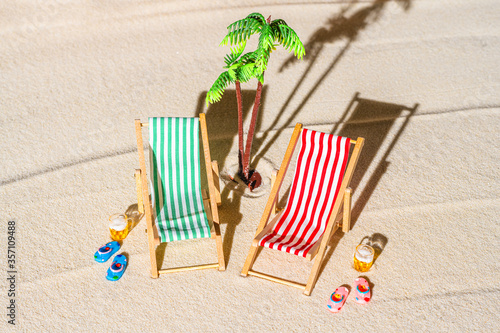 Aerial view of two deck chair, sunbed, lounge, big mug of beer, palm tree on sandy beach. Summer and travel concept. Minimalism