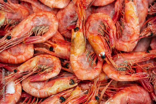 Lot of boiled-frozen wild shrimp with caviar cooked in sea water. Background of group small aquatic crustaceans. Prawn - Asian sea delicacy cuisine as an appetizer. Close-up flat lay of tasty seafood.