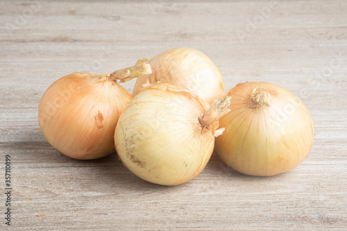 Four Sweet White Onions On A White Painted Panel Board