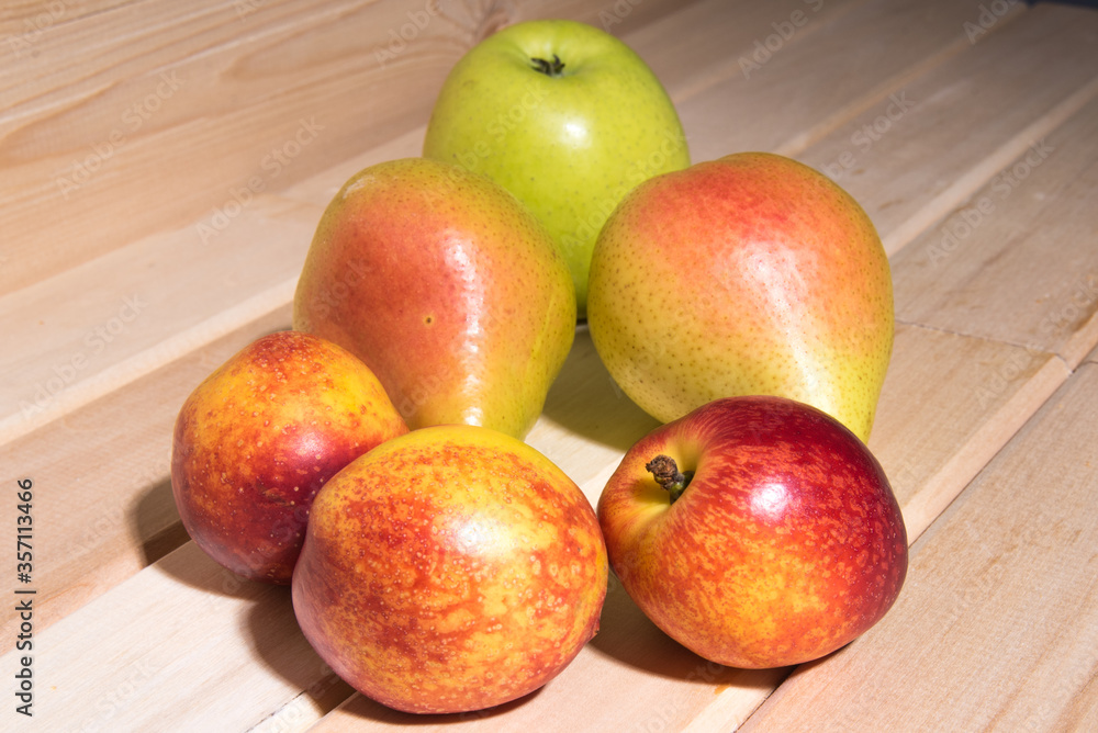 Red-yellow peaches, yellow pears, green apple lie on a wooden table close-up, fruit assorted Red-yellow peaches, yellow pears, green apple lie on a wooden table close-up, fruit assorted