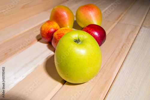 Red-yellow peaches, yellow pears, green apple lie on a wooden table close-up, fruit assorted