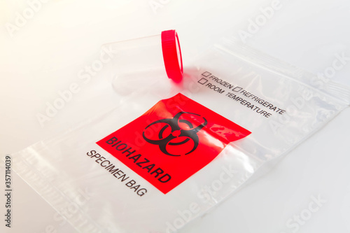Biohazard bag with plastic bottle for sputum collection. Concept of lab test for diagnosis of coronavirus infection. Selective focus