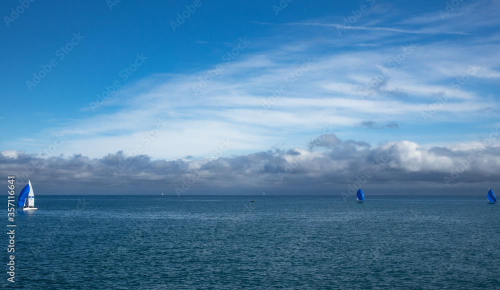 three sailbotas sailing on the sea, in the background a beautiful cloudy sky