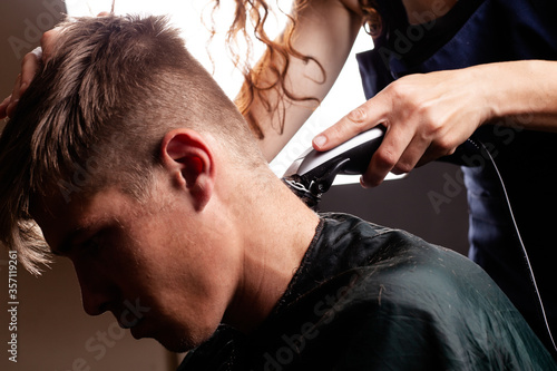 master hairdresser cuts guy making fashionable stylish haircut