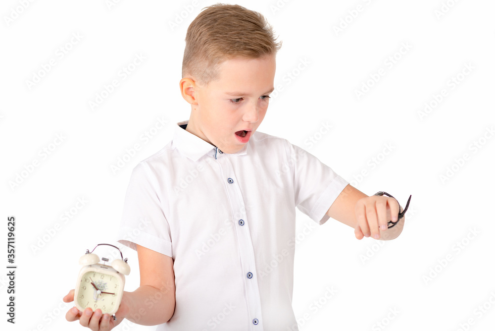 A portrait of surprised cute kid boy holding alarm clock a wristwatch in the other hand . Children and time management concept A portrait of surprised cute kid boy holding alarm clock a wristwatch in the other hand . Children and time management concept