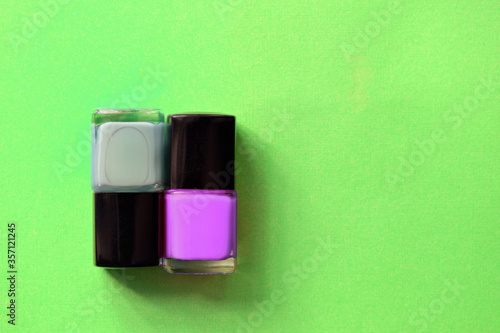 Nail polish bottles on a bright green background close-up. Manicure art cosmetic, nail art. Top view, copy space