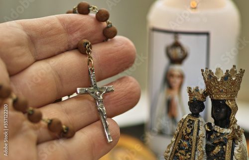 Human hand hold rosario. Saint Mary sculpture and candle light. Catholic equipment pray.