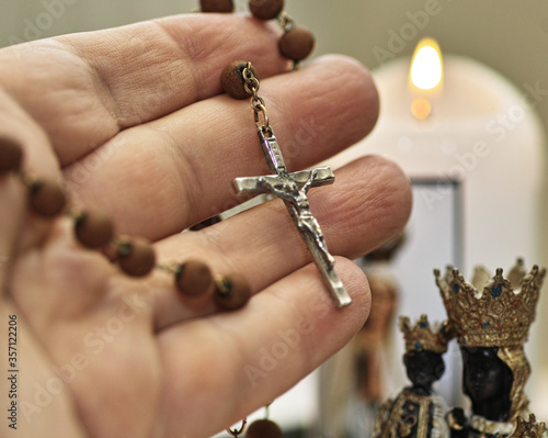 Human hand hold rosario. Saint Mary sculpture and candle light. Catholic equipment pray.