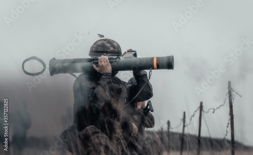 Closeup shot of a soldier in a field firing bazooka