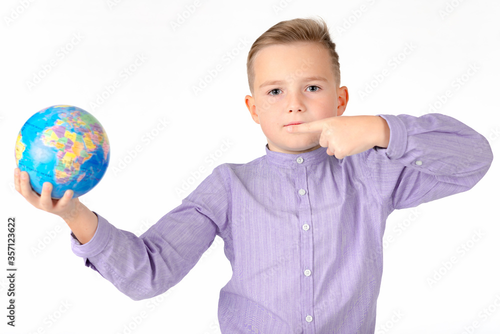 Playful young caucasian school boy holding a globe on white studio background.Boy is surprised shows at globe laughing Playful young caucasian school boy holding a globe on white studio background.Boy is surprised shows at globe laughing