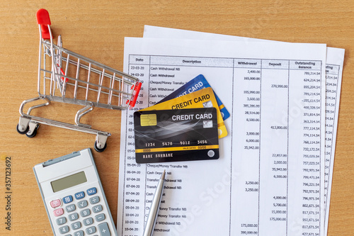 Credit cards and Cart supermarket and Calculator on Bank statement on a Wooden table