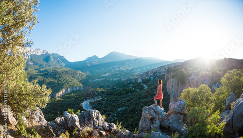 A girl in a dress stands on top of a mountain, a woman looks at a mountain valley