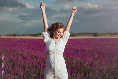 Beautiful girl in white dress is laughing on summer field of lavender