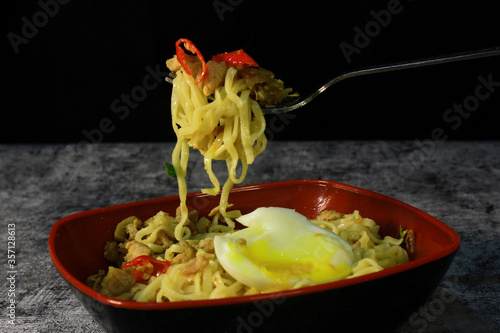 photo styling of fried noodles, topped with minced meat, crackers and chunks of red chili, some green spices and half-cooked eggs arouse the taste of noodle lovers. Spicy noodles have many fans
