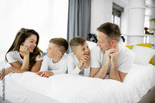 Young family enjoying in bed. Happy parents with sons relaxing in bed. © JustLife