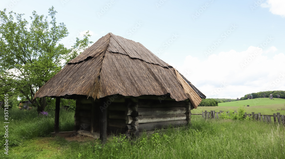 Old peasant Ukrainian house or barn in the summer with a thatched roof in the village. Pirogovo Museum in the open air of different regions of Ukraine.