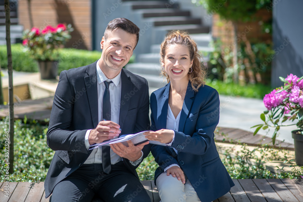 Well-dressed male client signing the contract and smiling Well-dressed male client signing the contract and smiling