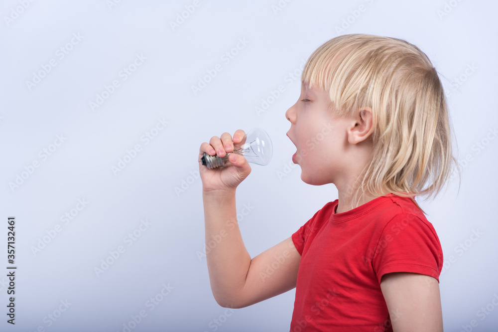 Boy playing with incandescent lamp. Child sings into lightbulb like into microphone Boy playing with incandescent lamp. Child sings into lightbulb like into microphone