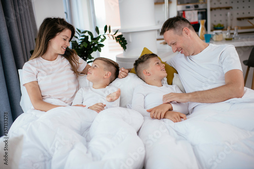 Beautiful parents with kids enjoying at home. Young family watching movie on lap top.