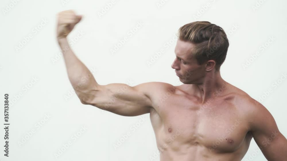 Shirtless man shows muscular pumped up biceps on his arm, white background Shirtless man shows muscular pumped up biceps on his arm, white background
