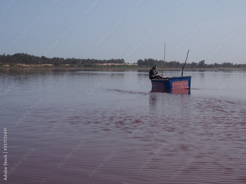Senegalese man taking a break on a boat on a pink lake, Lac Rose, Dakar, Senegal