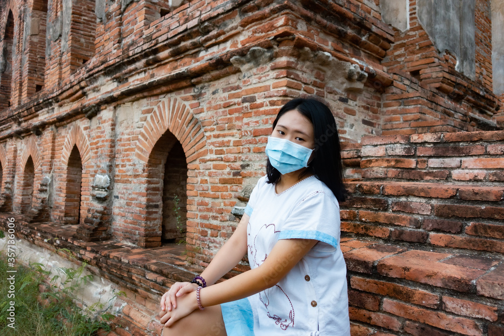Women tourist at ancient temple in Thailand with  her face mask