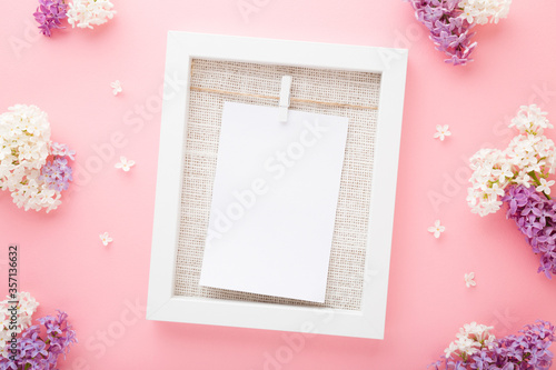 White frame with blank card. Colorful lilac blossoms on light pink table background. Pastel color. Empty place for cute, emotional, sentimental text, lovely quote or positive sayings. Top down view. © fotoduets