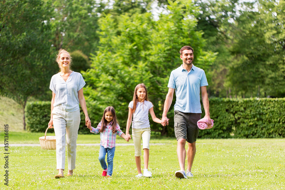 family, leisure and people concept - happy mother with picnic basket, father and two daughters walking in summer park family, leisure and people concept - happy mother with picnic basket, father and two daughters walking in summer park