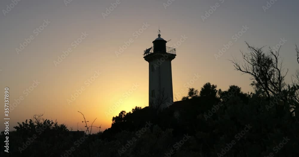 Low angle panning shot of lighthouse amidst silhouette plants against sky during sunset - Camargue, France Low angle panning shot of lighthouse amidst silhouette plants against sky during sunset - Camargue, France