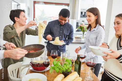 Gruppe Freunde serviert Spaghetti mit Tomatensauce in Küche photo