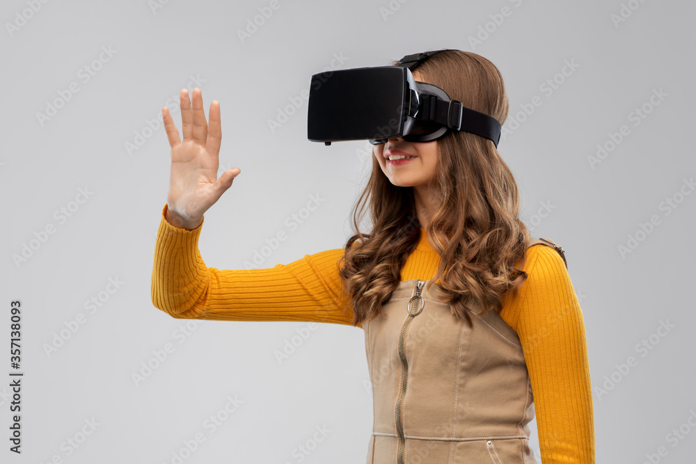 technology, augmented reality and entertainment concept - happy teenage girl with virtual headset or vr glasses over grey background technology, augmented reality and entertainment concept - happy teenage girl with virtual headset or vr glasses over grey background