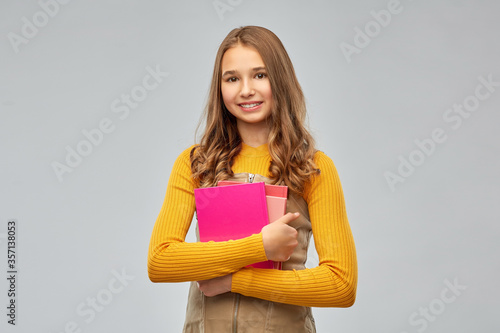 high school, education and people concept - smiling teenage student girl with books over grey background