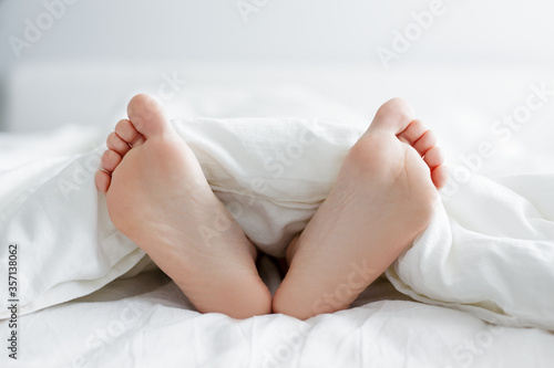 close up of female legs sticking out from the blanket © Di Studio