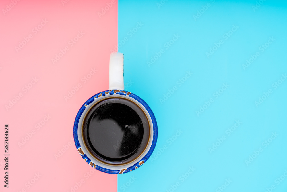 Cup of coffee on a gently pink and turquoise background. Top view flat lay.