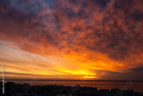 Beautiful dramatic sunset clouds in the sky over the sea and silhouette of the city Cape Town  South Africa. Bright Colors Of Sunset.