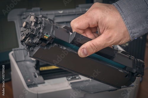 Man is replacing black cartridge in a printer