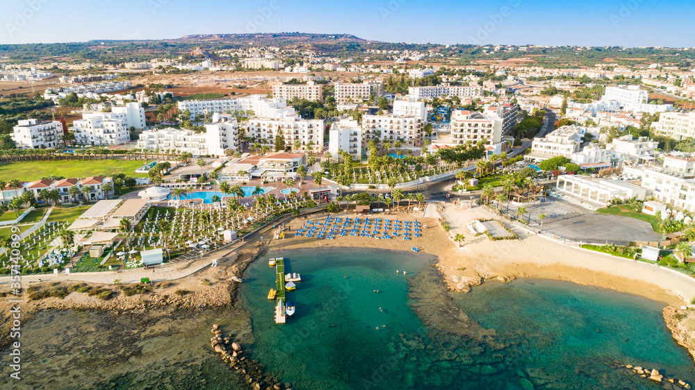 Aerial bird's eye view of Pernera beach in Protaras, Paralimni, Famagusta, Cyprus. Tourist attraction golden sandy bay with sunbeds, water sports, hotels, restaurant, people swimming in sea from above