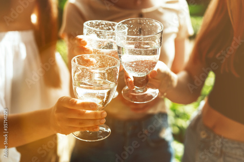 Close up shot of three glasses cheering, young girls, summer party
