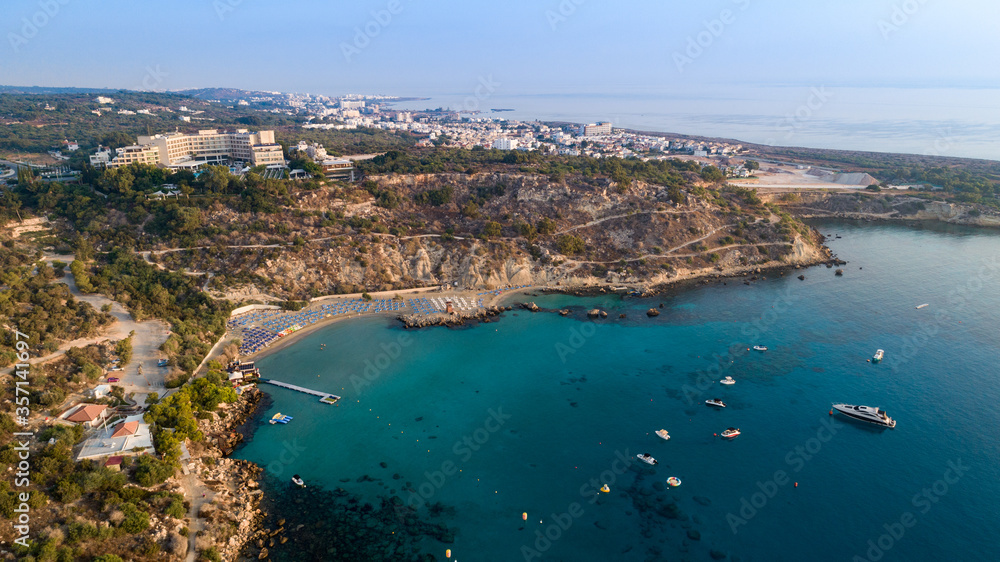 Aerial bird's eye view of Konnos beach, Cavo Greco Protaras, Paralimni, Famagusta, Cyprus. Famous tourist attraction golden sandy bay with boats, yachts in the sea, sunbeds, water sports, from above.