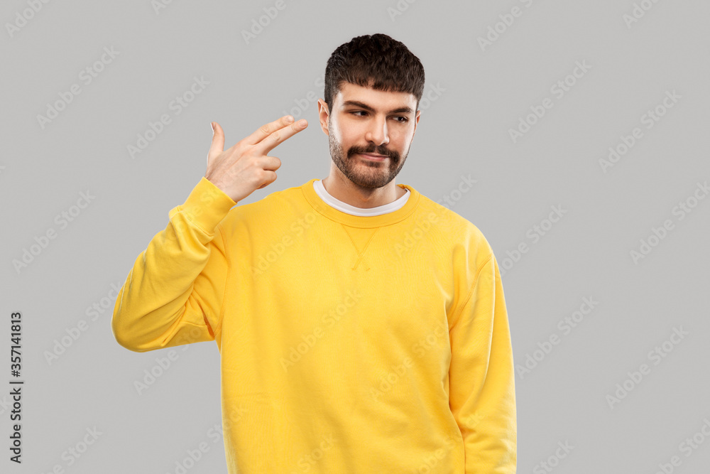 people, expression and stress concept - bored young man in yellow sweatshirt making headshot by finger gun gesture people, expression and stress concept - bored young man in yellow sweatshirt making headshot by finger gun gesture