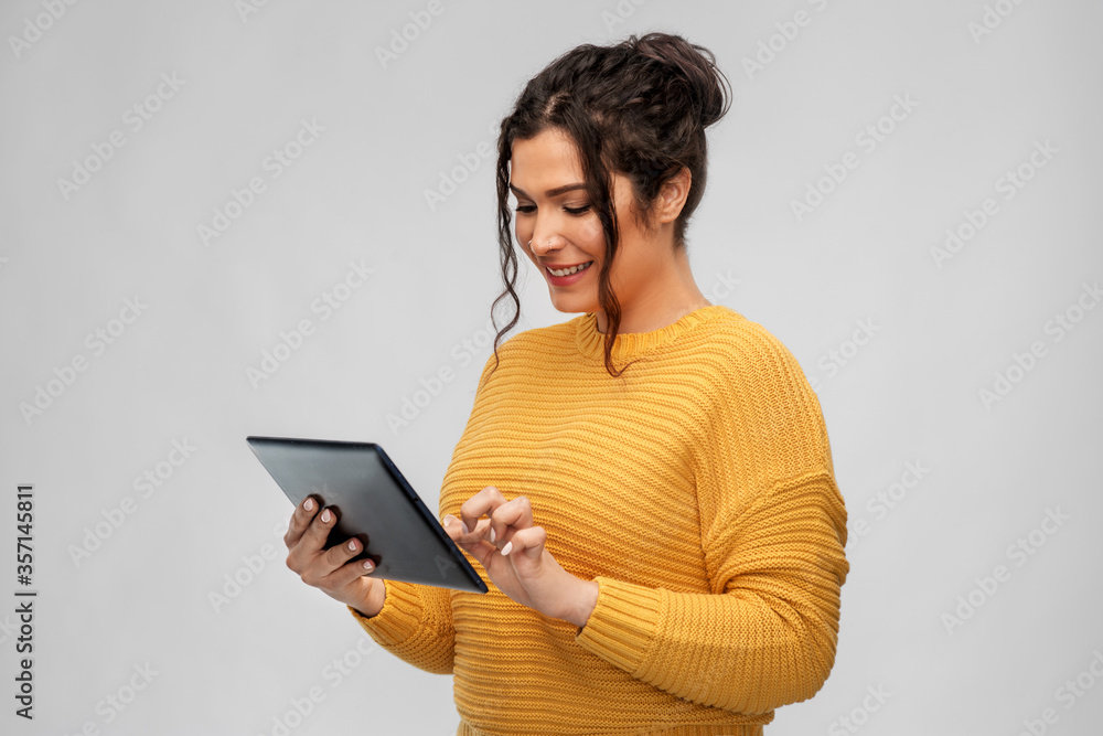 technology and people concept - happy woman using tablet computer over grey background technology and people concept - happy woman using tablet computer over grey background