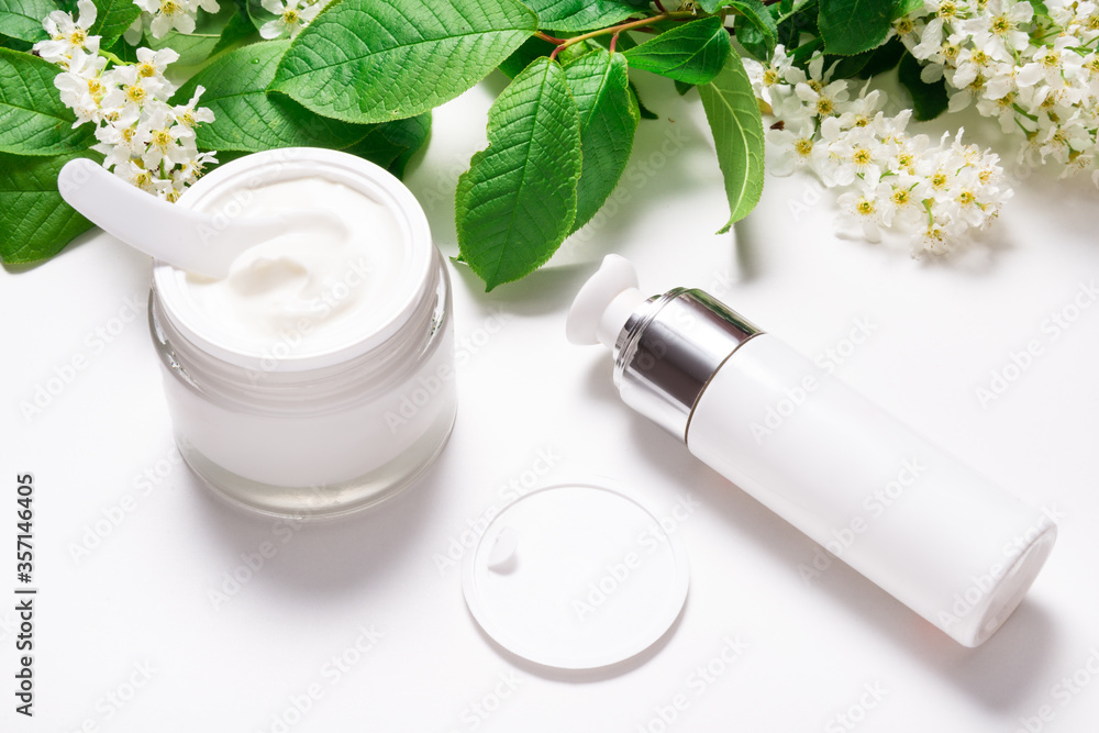 Face cream in jar on white table with bird cherry Face cream in jar on white table with bird cherry