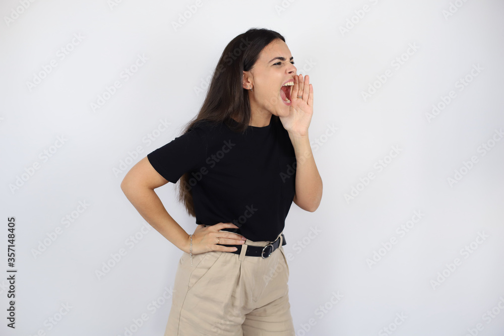 Young beautiful woman standing over white isolated screaming and closing her eyes Young beautiful woman standing over white isolated screaming and closing her eyes
