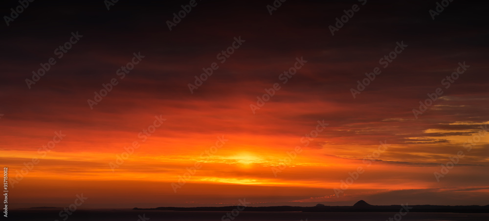 Panorama sunset/sunrise over the sea beside Edinburgh City, with flame clouds surrounding the sky