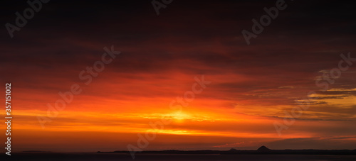 Panorama sunset/sunrise over the sea beside Edinburgh City, with flame clouds surrounding the sky