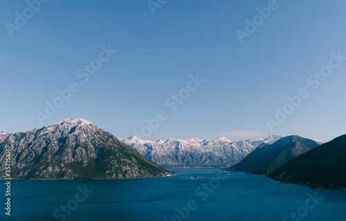 Panoramic views from the mountain at Koto Bay in Montenegro, in the area of Perast and Risan. Snow-capped mountain peaks in winter and blue sea water of the bay.